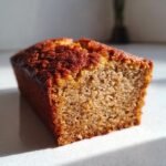 A close-up, sunlit slice showing the moist, golden crumb texture of homemade Banana Bread.
