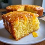Close-up of a moist slice of Orange Soda Cake topped with a thick, dripping orange glaze.