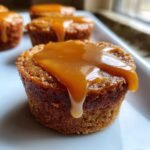 Close-up of a rich, baked Peanut Butter Caramel Minis topped with a thick, glossy caramel sauce dripping down the side.