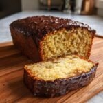 A loaf of Pretzel Chaos Cake, partially sliced, showing the moist crumb and rich chocolate glaze topping.