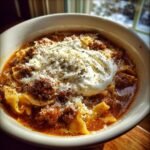 Close-up of a rich bowl of Sausage Lasagna Soup topped with a dollop of ricotta and grated Parmesan cheese.