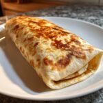 A golden-brown, toasted Smoked Chicken Burrito resting on a white plate.