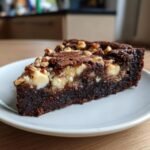 A rich, fudgy slice of White Chocolate Brownie Pizza studded with white chocolate chunks and topped with chopped nuts.