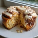 A soft, fluffy white chocolate cinnamon rolls cut open, generously drizzled with white chocolate icing.